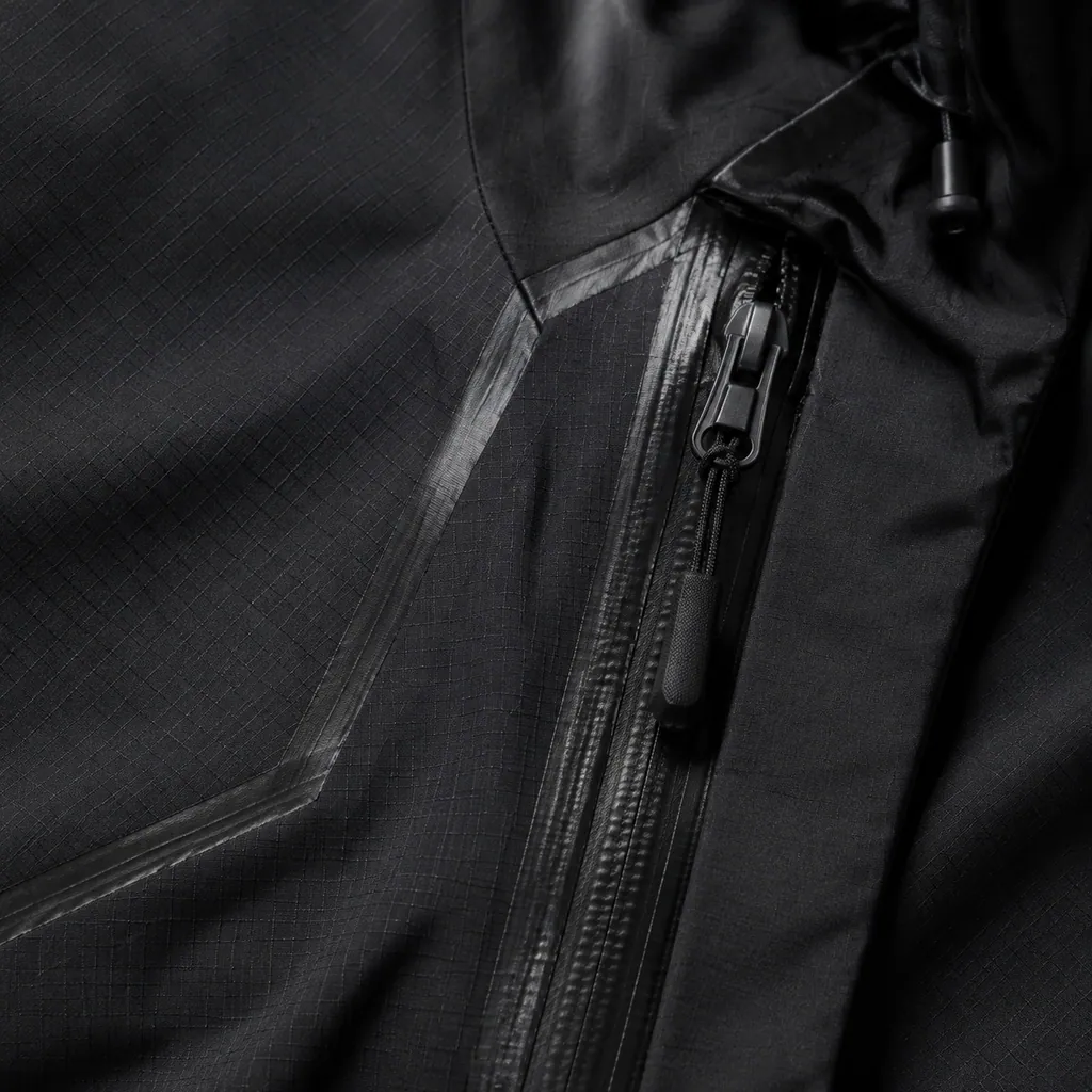 Varg 3L Hardshell Jacket photographed on wet dark rock under hard overcast light